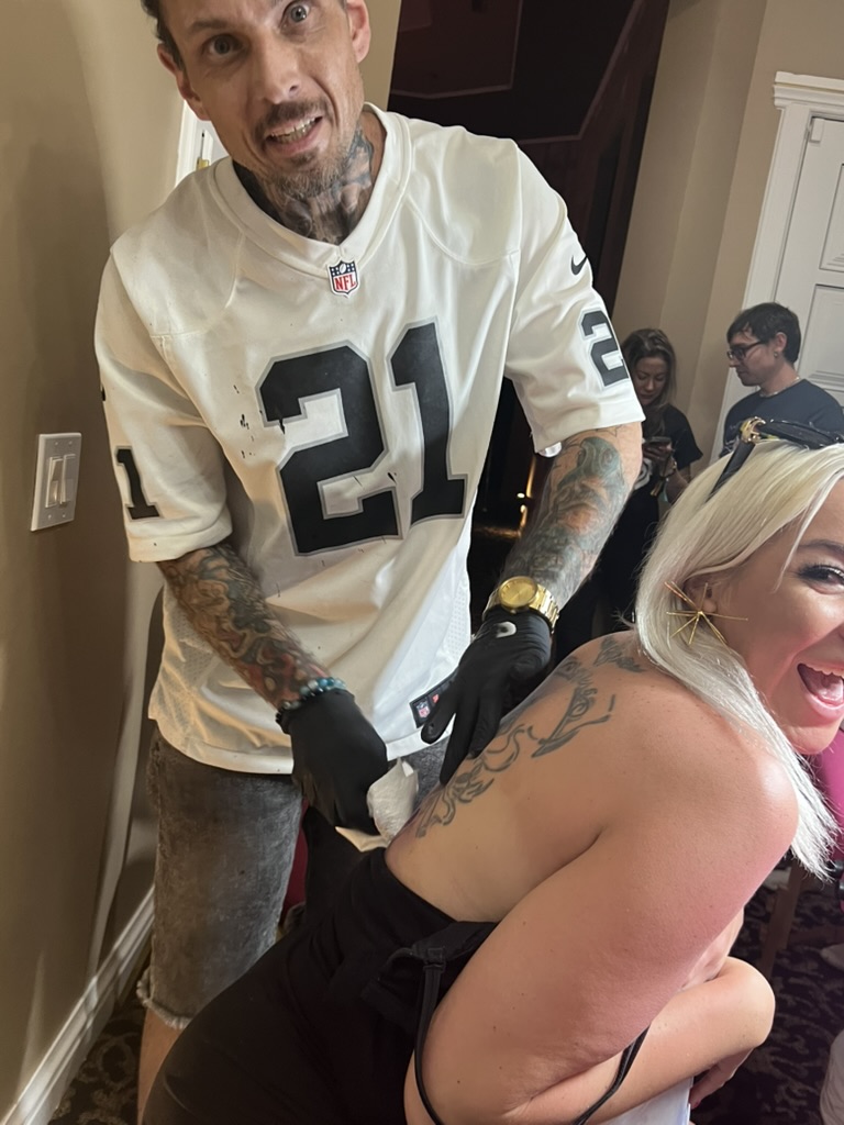 Joshua Cole wipes fresh phoenix back tattoo as laughing blonde client reacts offsite — Joshua…, Work of Art Tattoo & Piercing, Las Vegas