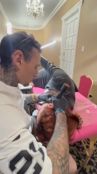 Joshua Cole tattoos woman's ear cartilage on pink table in chandelier-lit hotel suite — Joshua…, Work of Art Tattoo & Piercing, Las Vegas