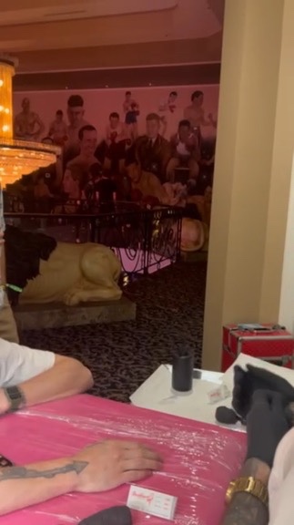 Arrow forearm tattoo on pink table beside lion statue and boxing mural at offsite — Joshua Cole…, Work of Art Tattoo & Piercing, Las Vegas