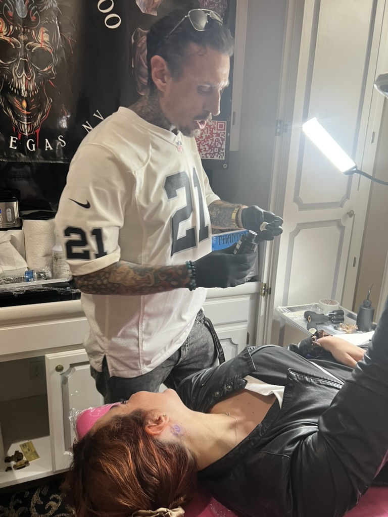 Joshua Cole opens ink bottle as client waits with purple neck stencil — Joshua Cole offsite…, Work of Art Tattoo & Piercing, Las Vegas