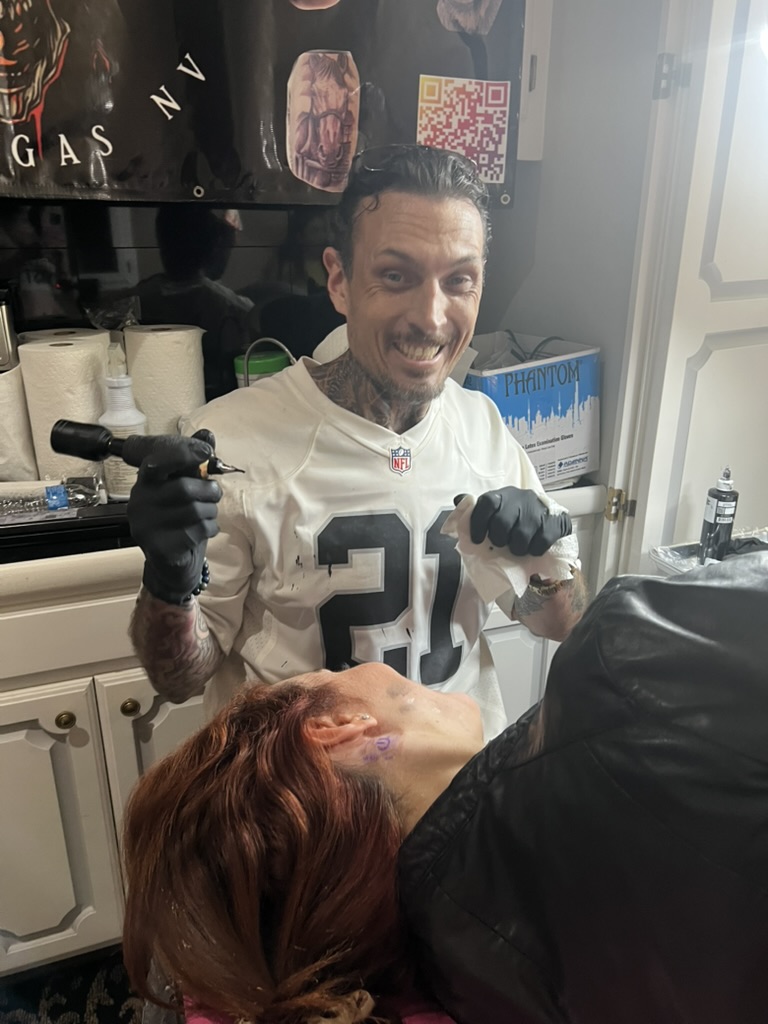 Joshua Cole tattoos jawline stencil on red-haired client in #21 jersey — Joshua Cole offsite…, Work of Art Tattoo & Piercing, Las Vegas