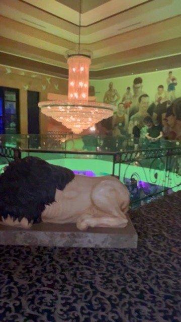 Lion statue overlooks boxing mural and chandelier in Vegas hotel mezzanine lounge — Joshua Cole…, Work of Art Tattoo & Piercing, Las Vegas