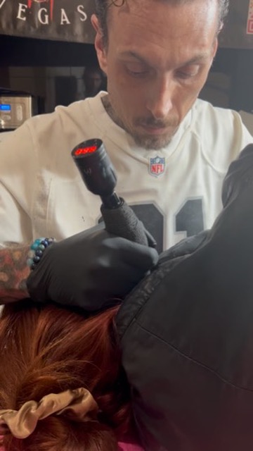 Joshua Cole tattoos power-button icon on neck behind client's ear at offsite event — Joshua Cole…, Work of Art Tattoo & Piercing, Las Vegas