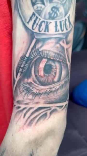 Black and grey all-seeing eye with FUCK LUCK banner and money bags on forearm. — Joshua Cole…, Work of Art Tattoo & Piercing, Las Vegas