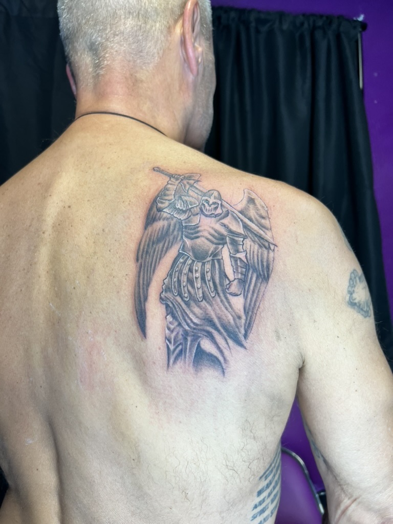 Detailed black and grey armored archangel with feathered wings on shoulder blade. — Joshua Cole…, Work of Art Tattoo & Piercing, Las Vegas