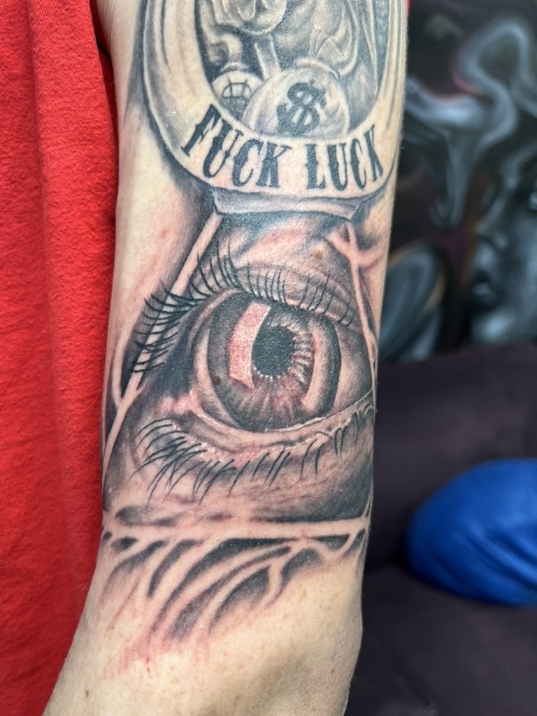 Realistic all-seeing eye with FUCK LUCK banner on outer bicep. — Joshua Cole, Work of Art Las…, Work of Art Tattoo & Piercing, Las Vegas