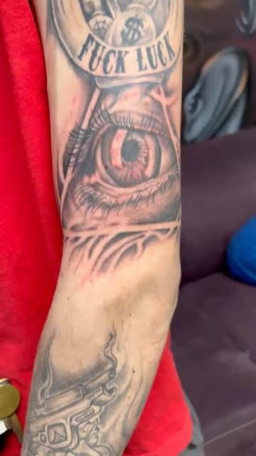 Hourglass with money bags, eye, and smoking pistol sleeve on upper arm. — Joshua Cole, Work of…, Work of Art Tattoo & Piercing, Las Vegas