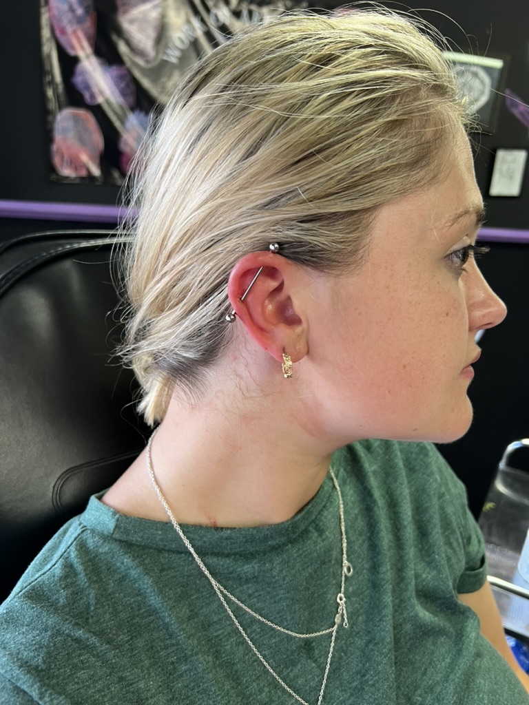 Blonde freckled client with silver industrial barbell and decorative gold lobe hoop earring…, Work of Art Tattoo & Piercing, Las Vegas