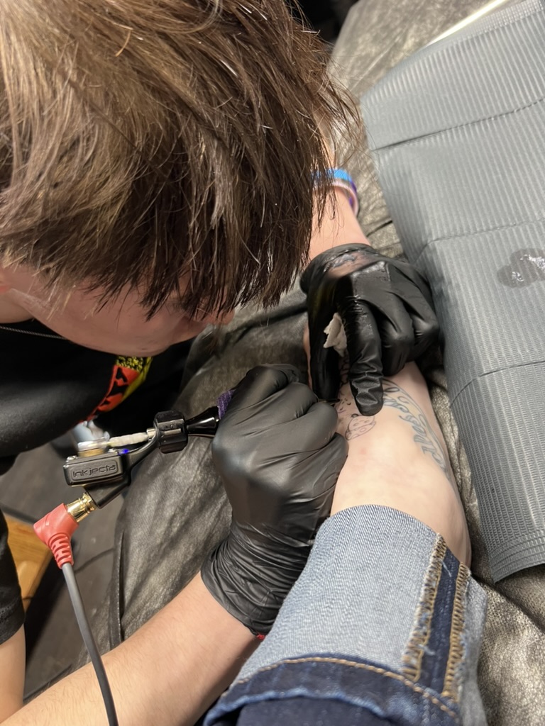 Joshua Cole applying a fine-line ankle tattoo with a rotary machine. — Joshua Cole, Work of Art…, Work of Art Tattoo & Piercing, Las Vegas