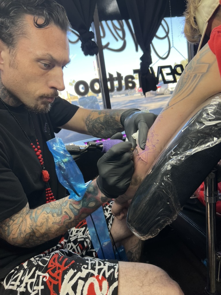 Joshua Cole inking a geometric star stencil on a client's forearm. — Joshua Cole, Work of Art…, Work of Art Tattoo & Piercing, Las Vegas