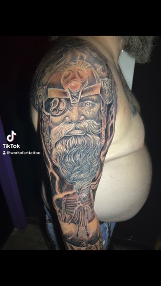 Odin portrait with gem helmet, gear monocle and lightning bolts wrapping shoulder and arm…, Work of Art Tattoo & Piercing, Las Vegas