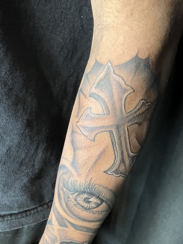 Beveled ornate cross above a realistic eye on outer forearm. — Joshua Cole, Work of Art Las Vegas, Work of Art Tattoo & Piercing, Las Vegas
