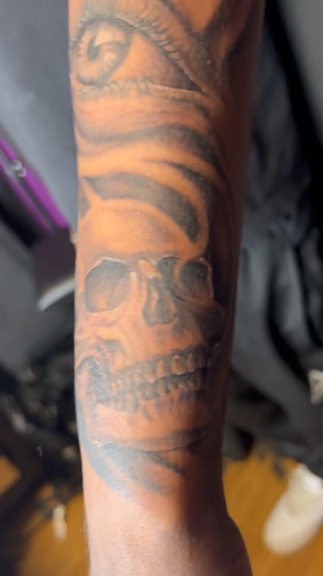 Black and grey realistic skull stacked beneath a detailed eye on the forearm. — Joshua Cole…, Work of Art Tattoo & Piercing, Las Vegas